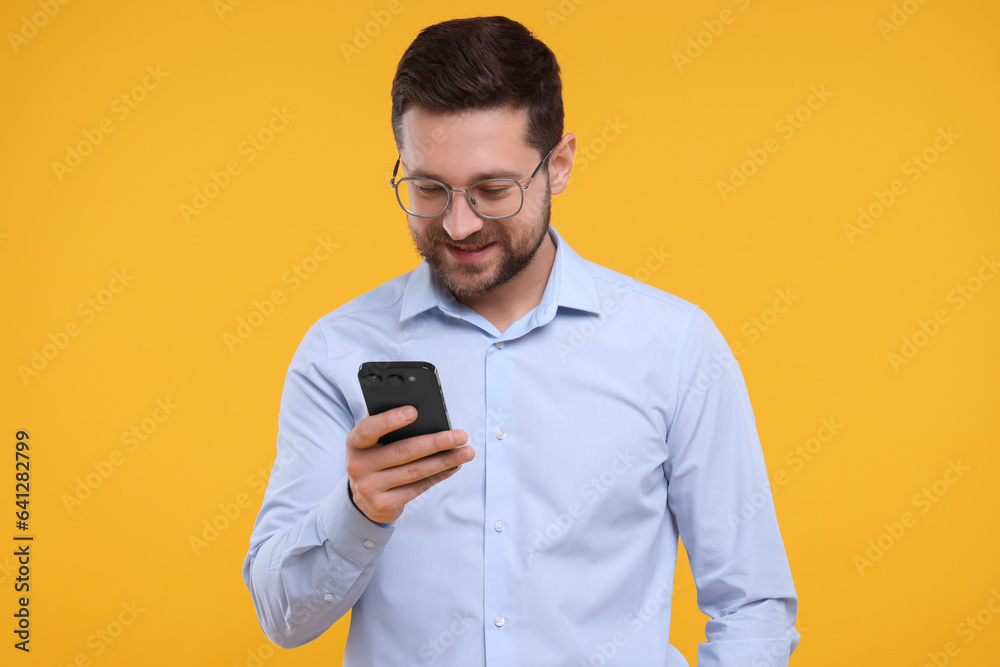 Happy man using smartphone on yellow background Happy man using smartphone on yellow background