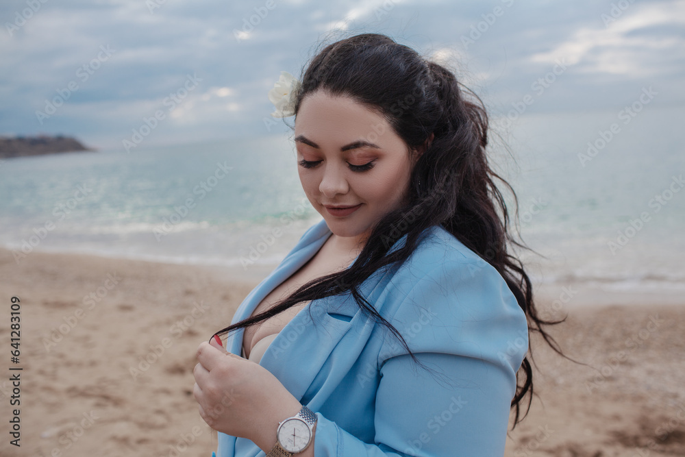 beautiful plus size woman walking in the beach against the sea. . The overweight model wearing style blue jacket and jeans beautiful plus size woman walking in the beach against the sea. . The overweight model wearing style blue jacket and jeans