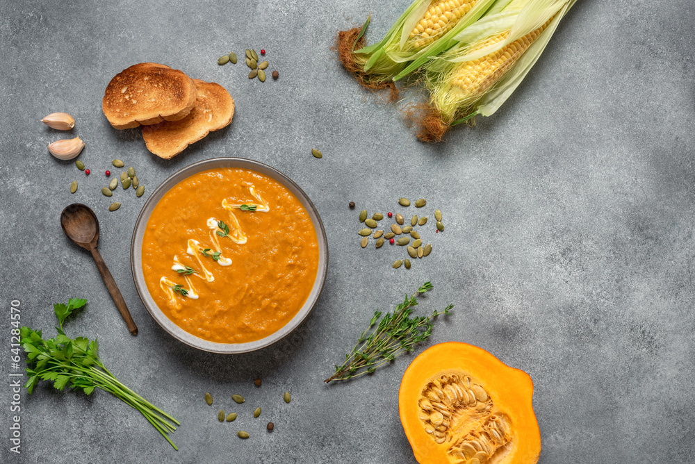 Homemade pumpkin cream soup, gray concrete background. Cozy thanksgiving dinner. Top view, flat lay.