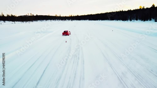 drone shot of red sports car driving slalom on ice photo