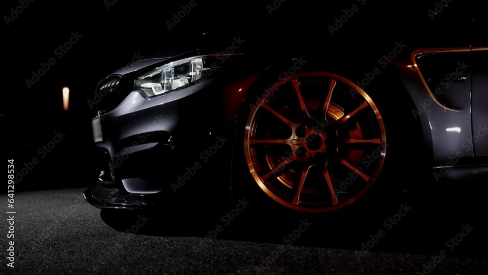 Detail shot of the front golden wheel with low profile tires of a sports car at night