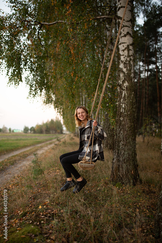 a beautiful girl swings on a swing in the middle of an autumn birch forest. autumn atmosphere in the forest