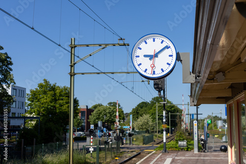 Dutch Train Station with Clock hanging on  the side.