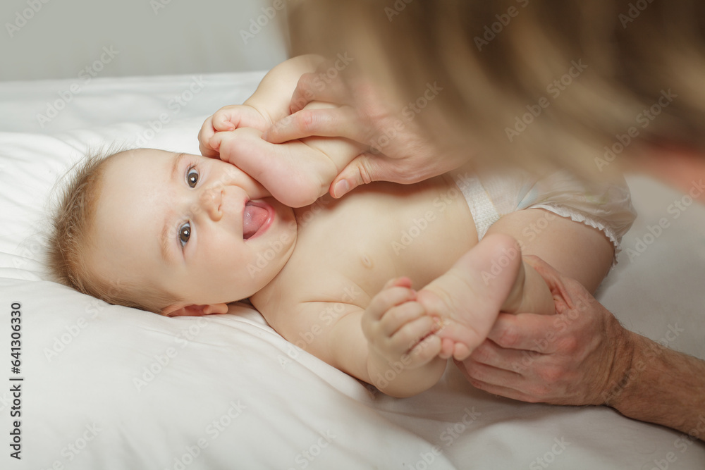 Joyful baby holding his feets while his father making belly and body massage for him Joyful baby holding his feets while his father making belly and body massage for him