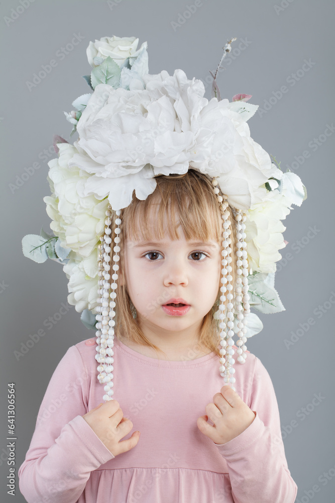 Fototapeta premium Portrait of adorable little girl in white flower hat on gray background