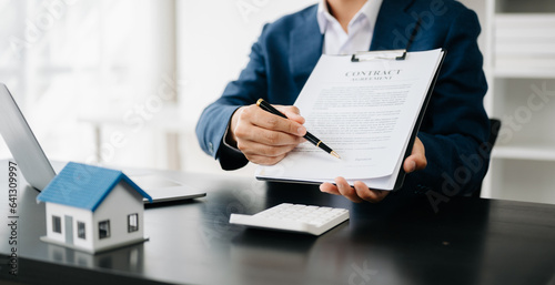 Buying a home or insurance deal, an insurance agent pointing a pen to those interested in renting a house, a contract, signing an Home buying agreement in office.