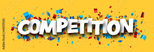 Competition sign with colorful cut out foil ribbon confetti on yellow background.