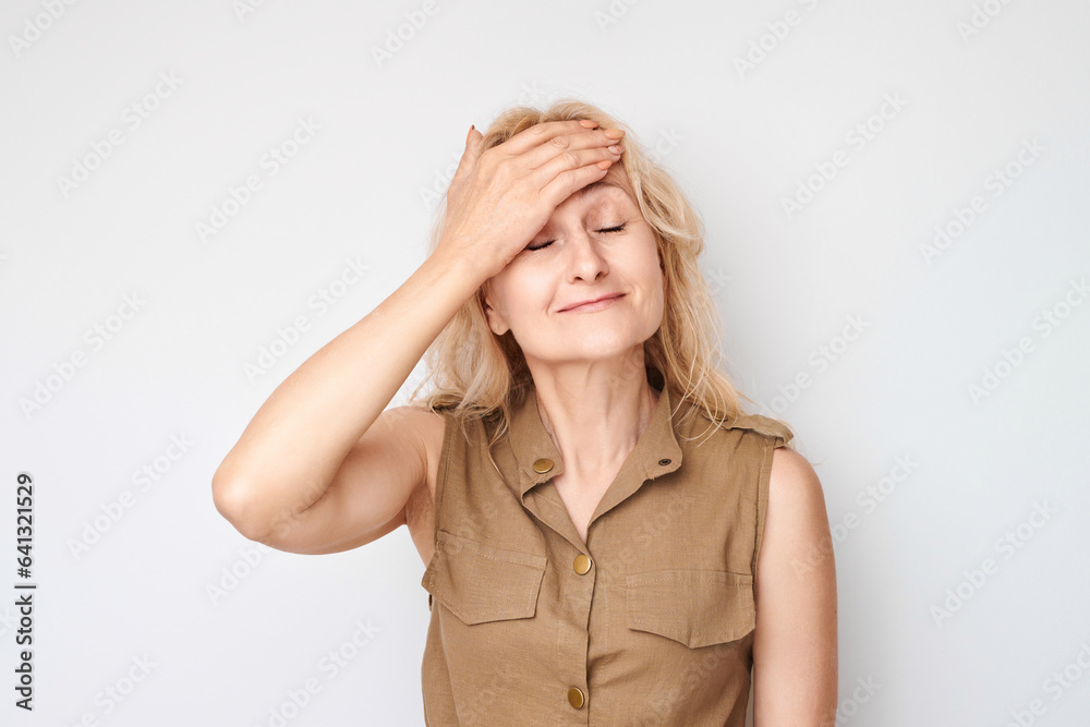 Portrait of disappointed 50 year old woman with face palm gesture isolated on white studio background. What have I done concept Portrait of disappointed 50 year old woman with face palm gesture isolated on white studio background. What have I done concept