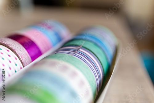 A portrait of colorful washi tape in different patterns and colors in a box. The decorative rolls are ready to use to decorate a gift or post card, gift or to use for interior design like on a wall.