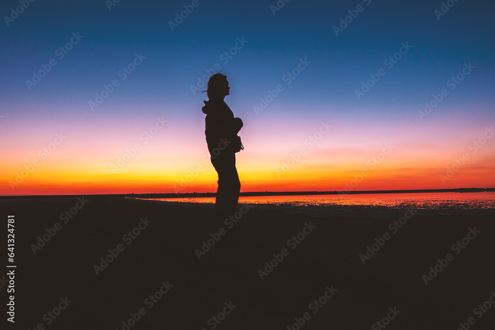 Woman's silhouette on a red-yellow sunset background.