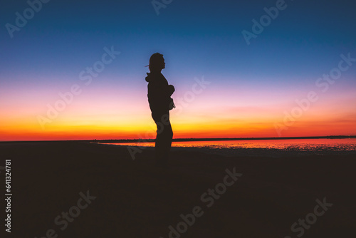 Woman's silhouette on a red-yellow sunset background.