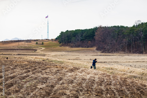 KIJONG VILLAGE, NORTH KOREA: farmer and giant pole with North Korean flag in countryside, near Panmunjom and DMZ, Democratic Peoples's Republic of Korea (DPRK) photo