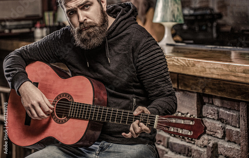 Music concept. Bearded guitarist plays. Guitars and strings. Bearded man playing guitar, holding an acoustic guitar in his hands