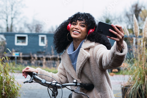 Black girl with bicycle taking selfie by mobile phone in the street photo