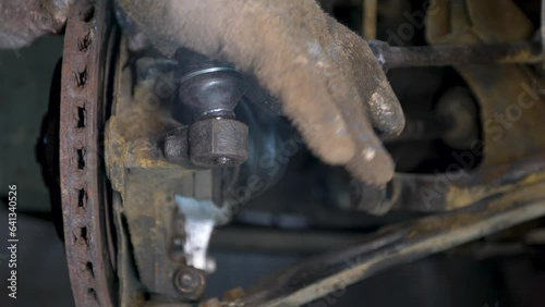 The hands oTie rod in the hands of an auto mechanic. Checking the technical condition of a new spare part before installation.f a mechanic install the steering rod of the car. photo