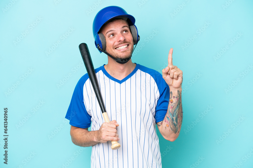 Baseball player with helmet and bat isolated on blue background pointing up a great idea