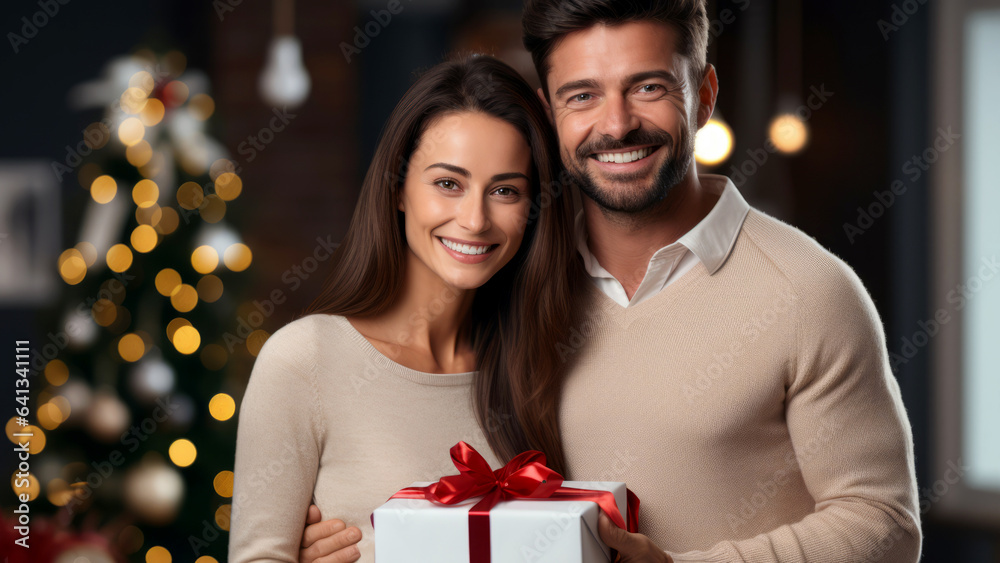Smiling European couple with a wrapped Christmas gift in a decorated living room. Close-up portrait of a happy Caucasian pair holding a covered New Year present at home. Winter Holidays concept. Smiling European couple with a wrapped Christmas gift in a decorated living room. Close-up portrait of a happy Caucasian pair holding a covered New Year present at home. Winter Holidays concept.