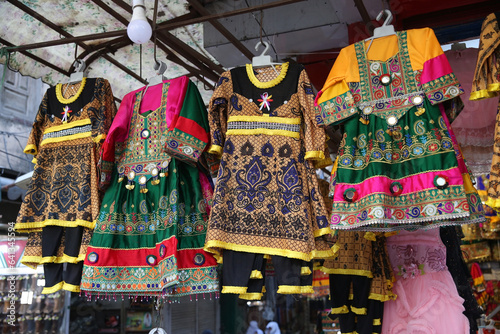 Traditional national dresses are on market in Peshawar city, Pakistan. Pashtun style. Pashtun fashion. Bazaar in Peshawar city, Pakistan. Pakistani fair, shop with folk dresses. Asian street market photo