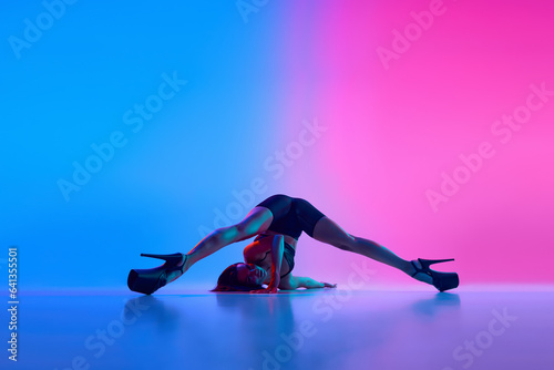 Flexibility. Woman dancing modern dance style over gradient blue pink studio background in neon light.