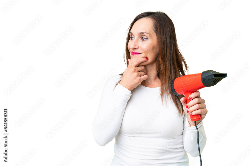Middle age woman holding a hairdryer over isolated chroma key background thinking an idea and looking side Middle age woman holding a hairdryer over isolated chroma key background thinking an idea and looking side