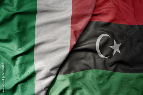 big waving national colorful flag of italy and national flag of libya .