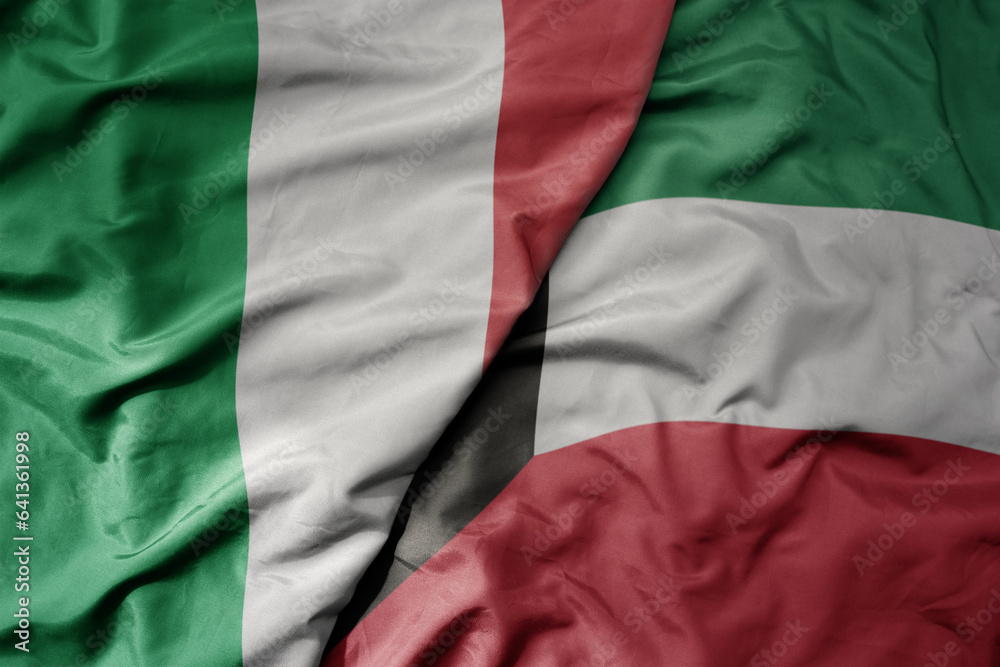 big waving national colorful flag of italy and national flag of kuwait .