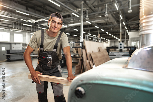 Male carpenter using some woodworking tools for his work in a factory