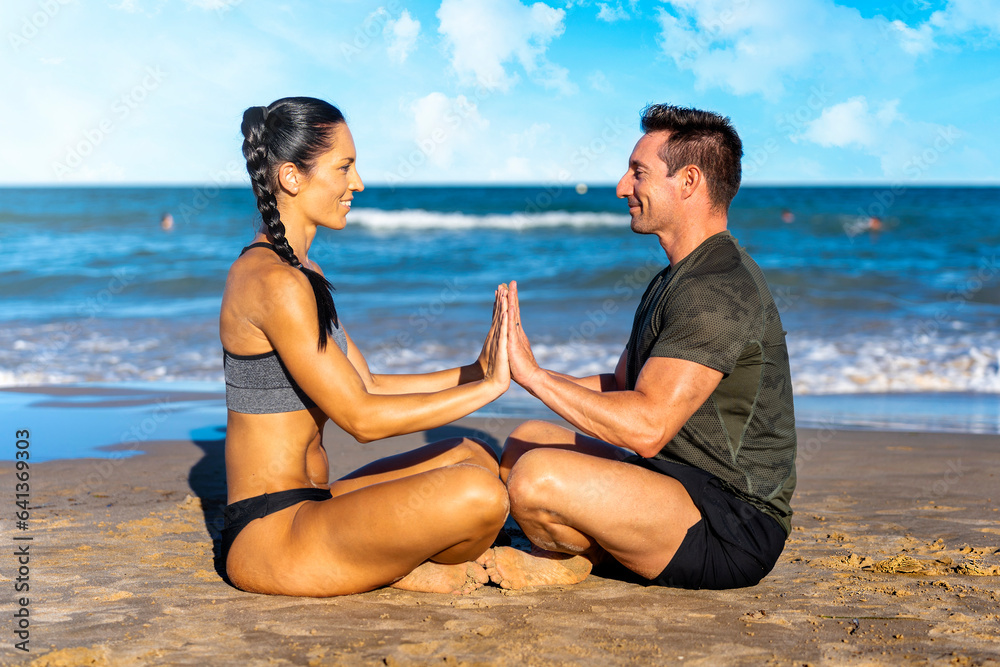 Fototapeta premium Couple making yoga exercises on beach