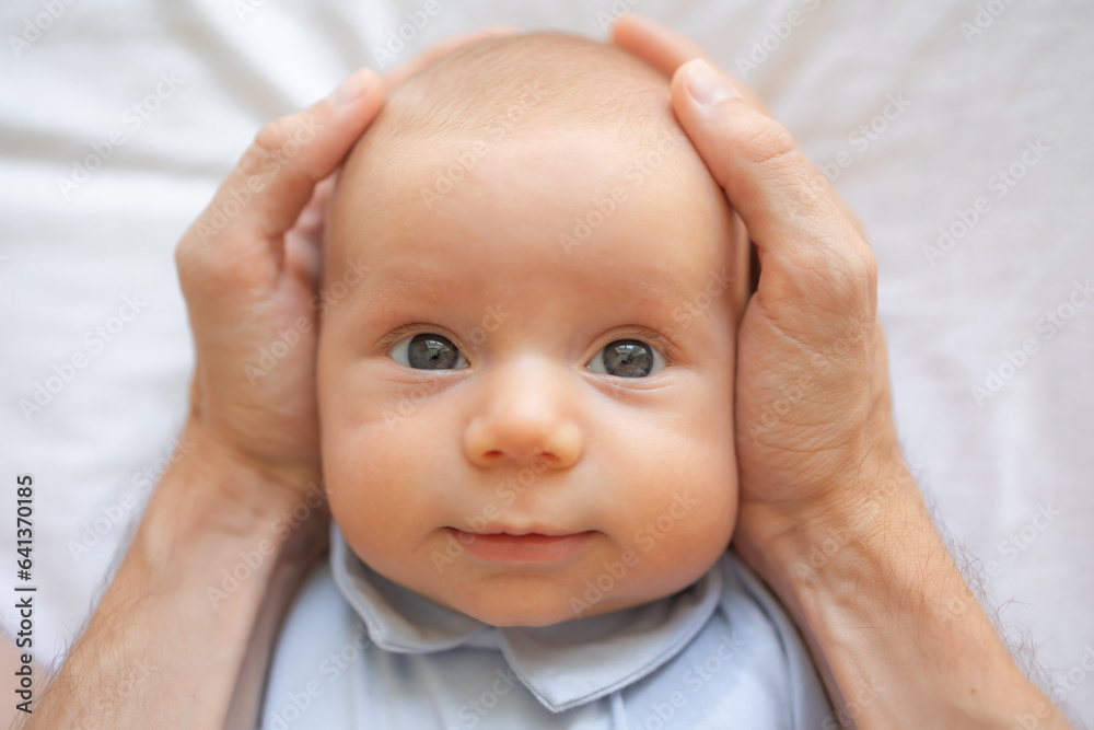 Close up of caucasian cute newborn baby smiling in father hands. Two months child in male hands. Close up of caucasian cute newborn baby smiling in father hands. Two months child in male hands.