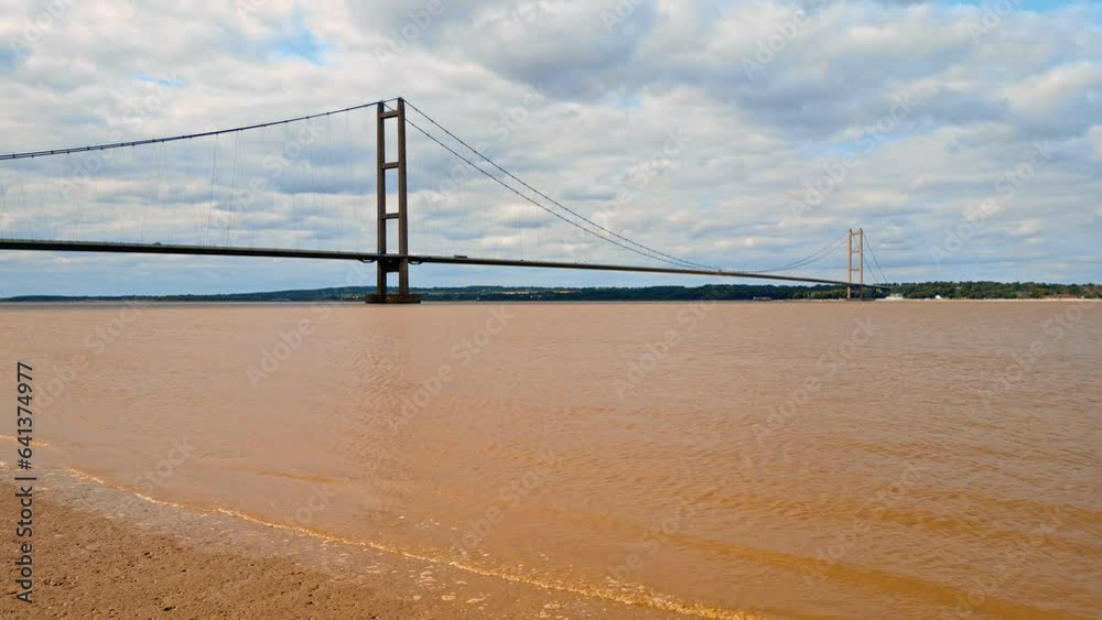 Aerial drone view of Humber Bridge, 12th largest suspension span, gracefully crossing River Humber, connecting Lincolnshire to Humberside with traffic. Aerial drone view of Humber Bridge, 12th largest suspension span, gracefully crossing River Humber, connecting Lincolnshire to Humberside with traffic.