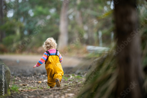 baby walking in a park in yellow overalls