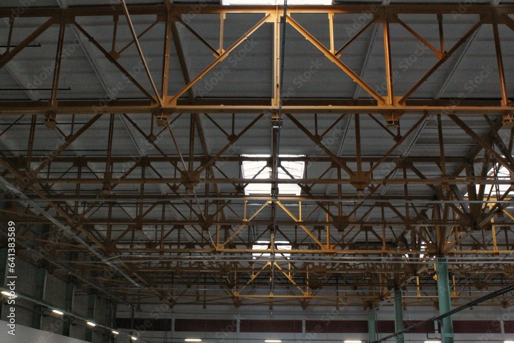 Interior of empty factory. Modern design of warehouse industrial building. Urban loft style on workshop space with metal constructions and pipes under the beton ceiling. Steel roof frame