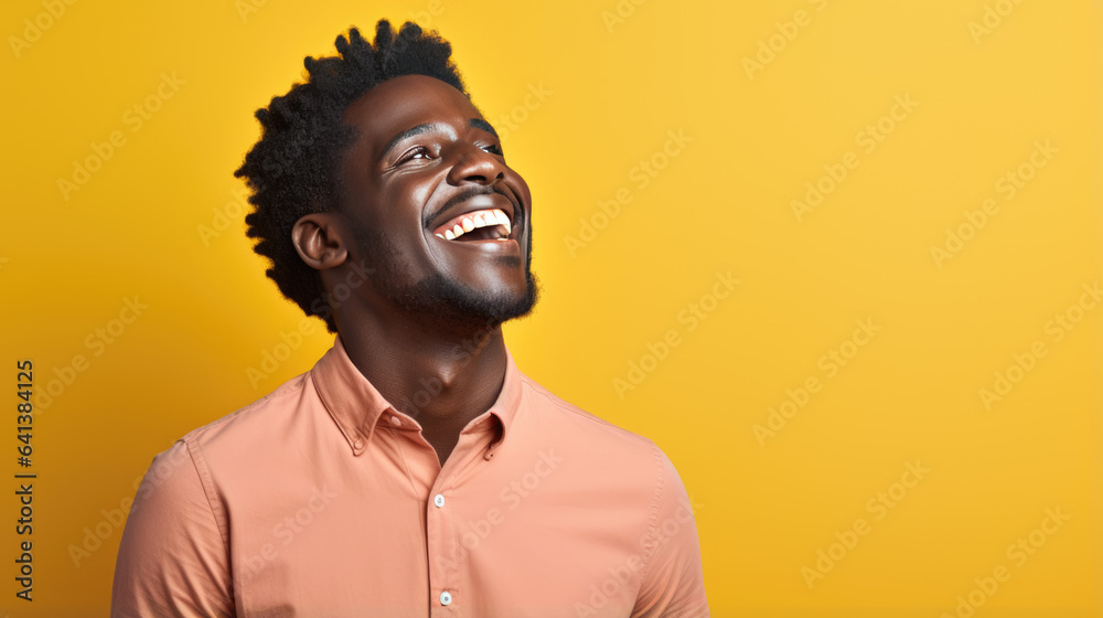 Young man laughs against a yellow background. Young man laughs against a yellow background.