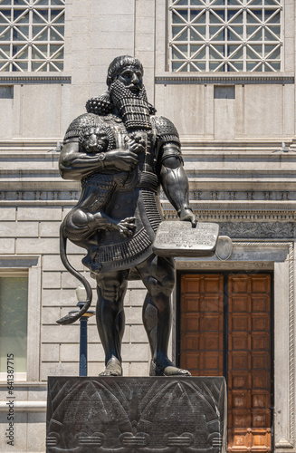 San Francisco, CA, USA - July 12, 2023: Closeup, Statue of historic Ashurbanipal Assyrian king or Enkidu holding a wriggling lion and a tablet, at south facade of Asian Art Museum. photo