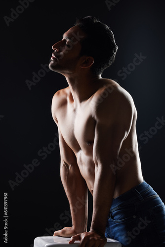 Topless, sexy and man in dark studio for fitness inspiration, beauty aesthetic or casual fashion. Strong body and shirtless male model with muscle, black background and healthy art with lighting