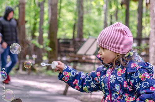 Cute girl playing with soap bubbles in park
