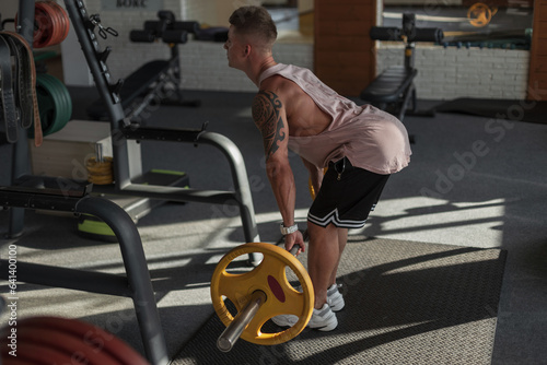Cool strong athletic muscular man doing exercise with weights in the sport gym