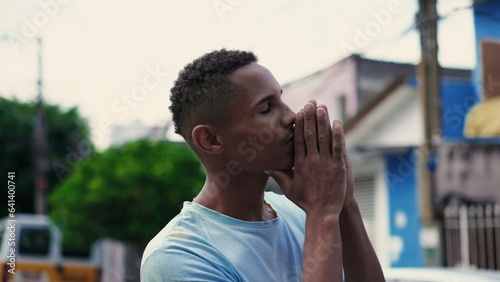 Religious South American Black Man Praying to God in Urban Street, Faithful Brazilian Gazing Upwards for Divine Support