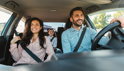 Happy european family of three riding car, traveling by automobile together, parents and daughter enjoying road trip