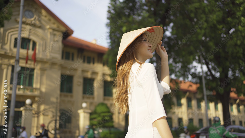 Portrait of Asian Vietnamese woman with Vietnam dress and straw hat in tree corridor in Hanoi. People lifestyle.