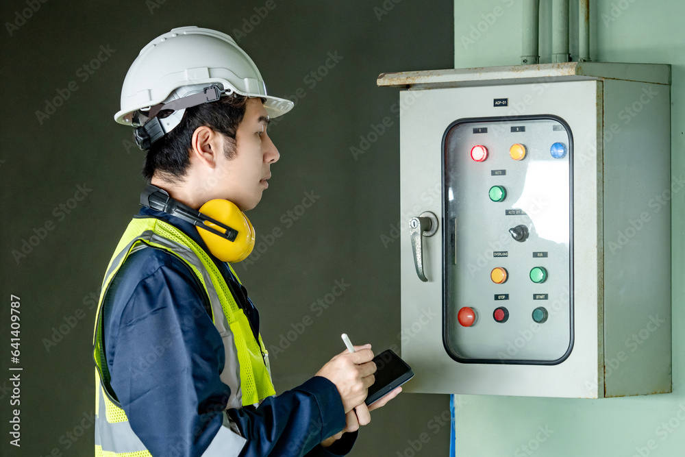 © Summer Paradive - Building inspector man using digital tablet checking air pressurized fan system cabinet. Asian male worker in green vest, ear muffs and safety helmet working for building maintenance inspection © Summer Paradive - Building inspector man using digital tablet checking air pressurized fan system cabinet. Asian male worker in green vest, ear muffs and safety helmet working for building maintenance inspection