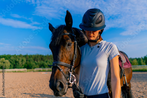 A helmeted rider leads her beautiful black horse by the harness in the riding arena during a horseback ride © Guys Who Shoot