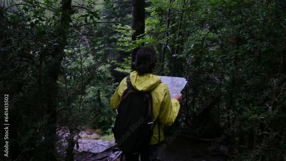 40 year old woman alone in the forest mountain with waterfall using map to orient herself and find way. Concept of freedom, empowerment, personal development, finding one's own path and adventure 40 year old woman alone in the forest mountain with waterfall using map to orient herself and find way. Concept of freedom, empowerment, personal development, finding one's own path and adventure