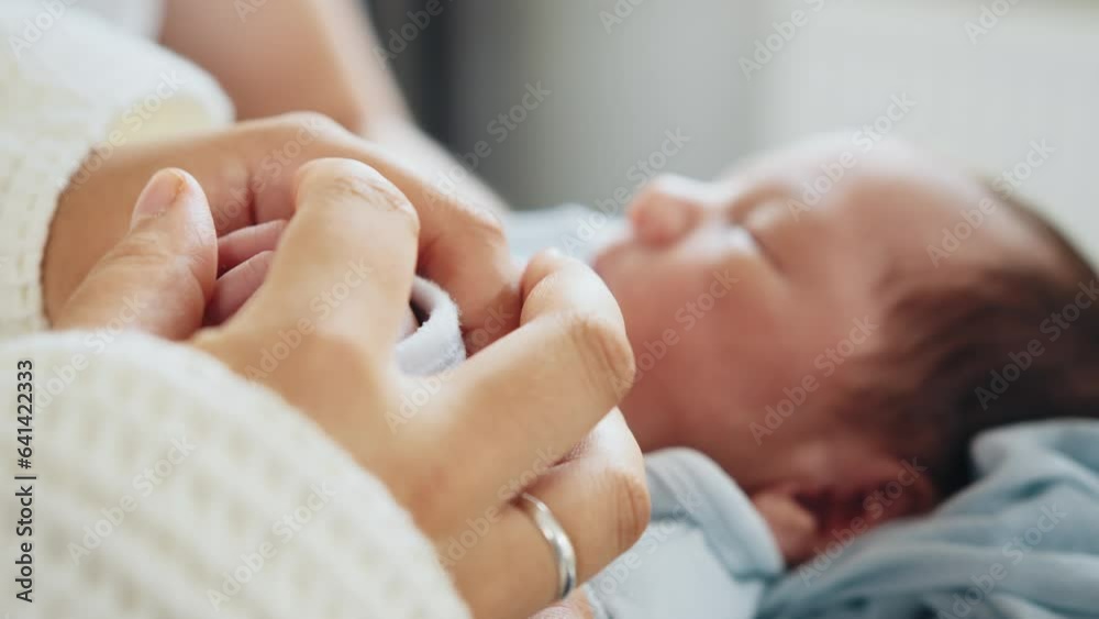 The newborn is holding a finger of mother on a white background. Healthcare, pediatrics. Newborn. Unrecognizable family admiring their newborn baby at hospital with mother at post natal department