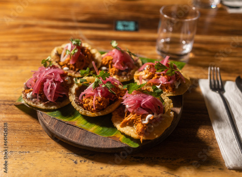 Obraz na płótnie Traditional Mexican cuisine with tortilla and red onions served on top of banana leaf in a wooden plate with transparent glass in the background w salonie