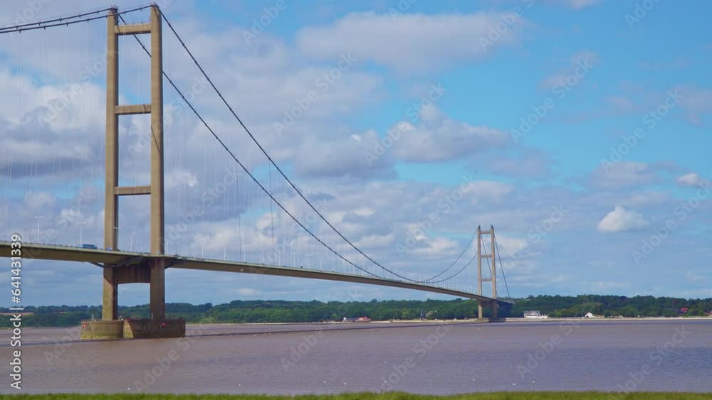 Aerial drone view of Humber Bridge, 12th largest suspension span, gracefully crossing River Humber, connecting Lincolnshire to Humberside with traffic. Aerial drone view of Humber Bridge, 12th largest suspension span, gracefully crossing River Humber, connecting Lincolnshire to Humberside with traffic.