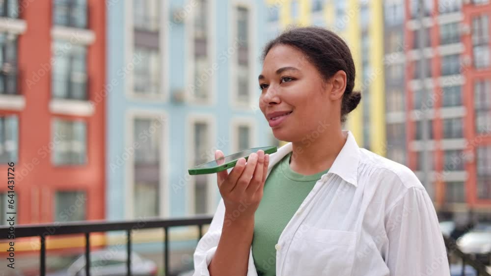 Charming African American Lady Standing Outside and Recording Voice Message Outside. Positive Young Woman Activating Her Mobile Assistant. People And Technology Concept