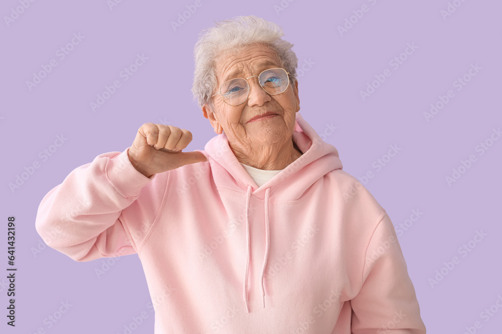 Senior woman pointing at herself on lilac background Senior woman pointing at herself on lilac background