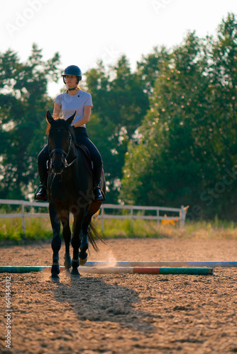 A rider dressed in a helmet rides her beautiful black horse in a riding arena during a horseback ride