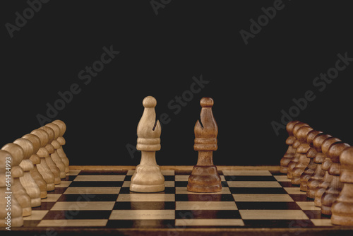 Concept of rivalry between teams and leaders. Two bishops, each with many pawns following, face off on the chessboard. Black background with copy space. photo